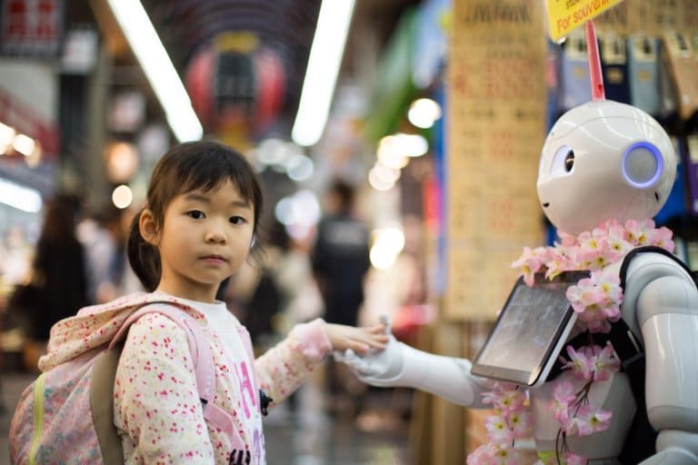 Ung jente som håndhilser med en robot