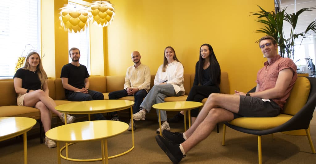 sommerstudenter i Computas sitter i en sofagruppe i et gult rom